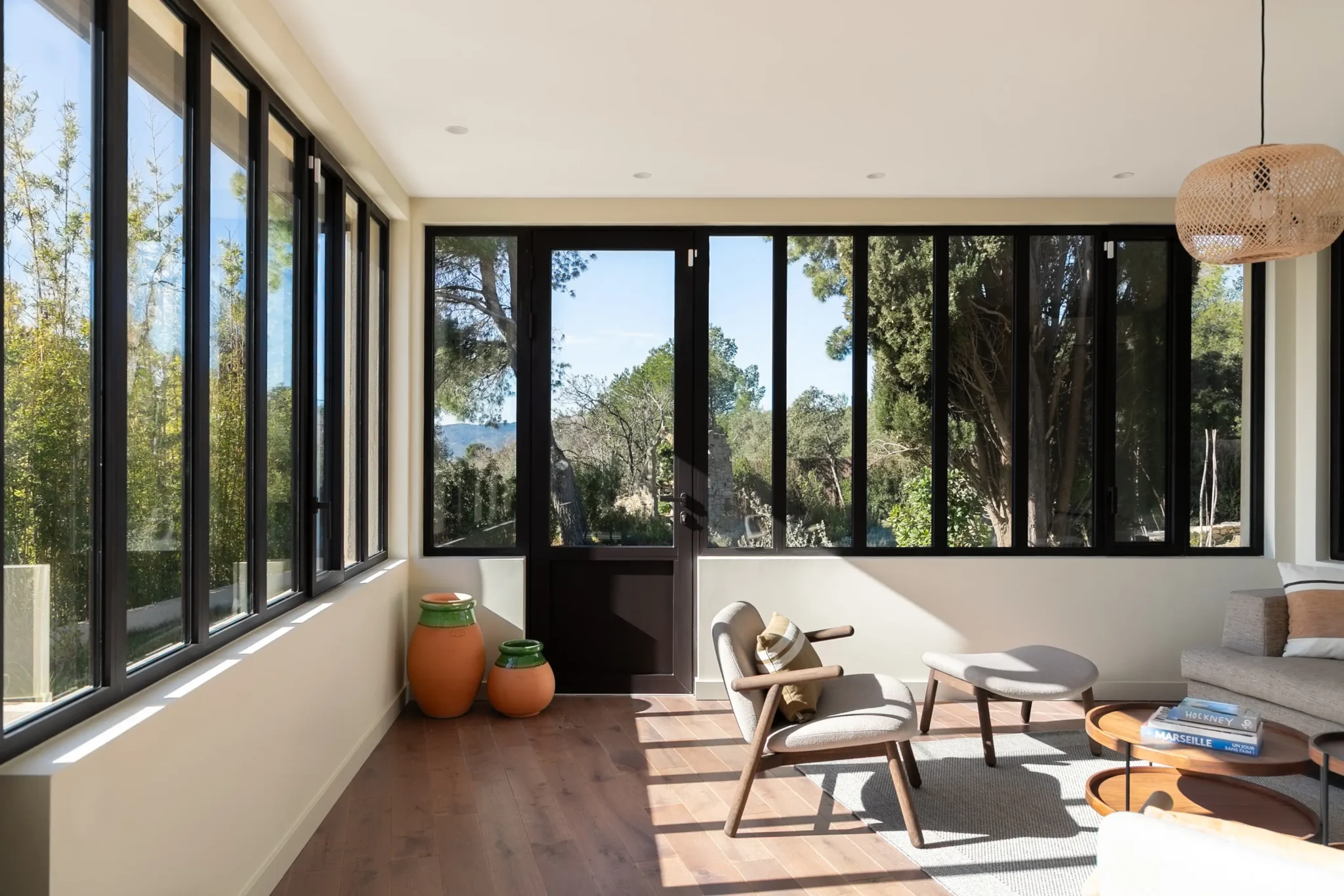 extension de maison véranda avec verrière style atelier bibliothèque métal AMPM canapé et fauteuils Bolia sol en parquet foncé