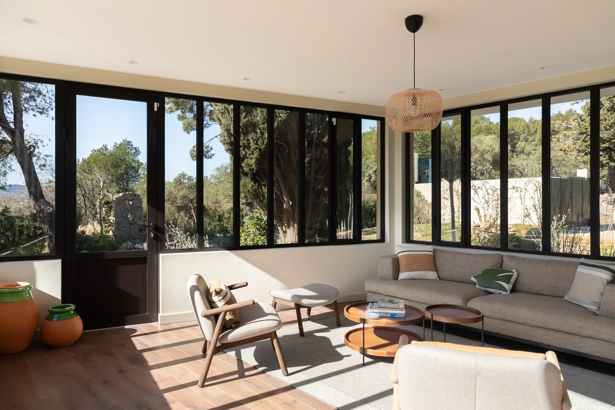 extension de maison véranda avec verrière style atelier bibliothèque métal AMPM canapé et fauteuils Bolia sol en parquet foncé