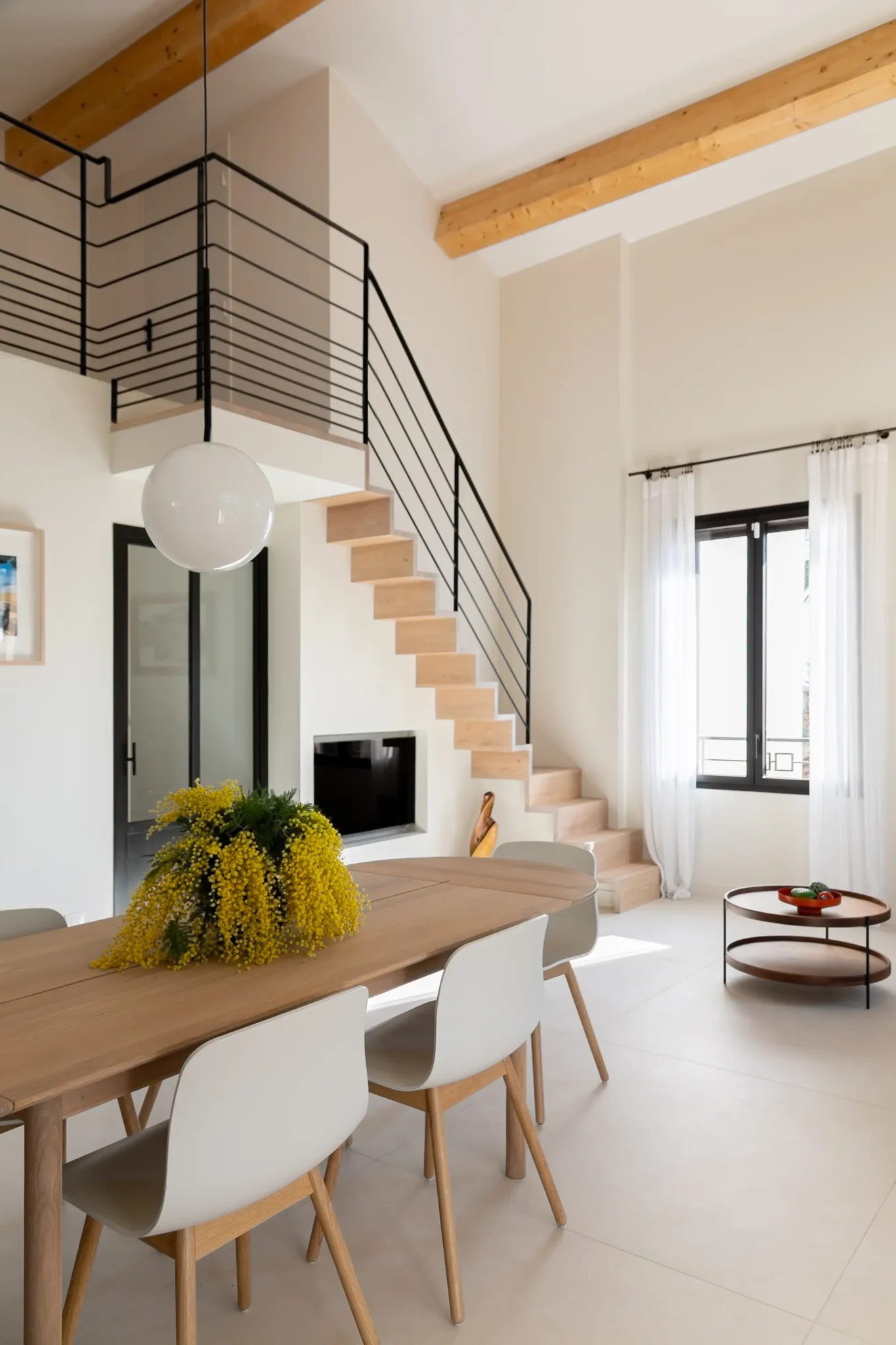 alle à manger avec table de chez Bolia porte vitrée sur mesure en fer forgé escalier gain de place avec main courante en métal noir carrelage sol grand format effet béton ciré