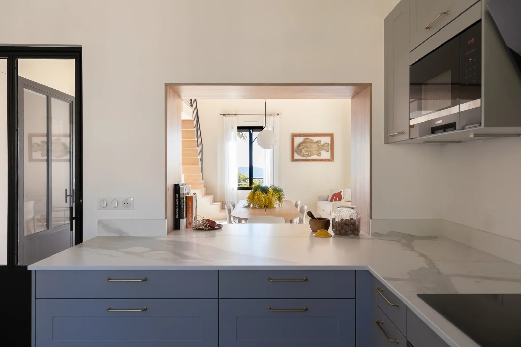 rénovation de maison cuisine avec plan de travail effet marbre ouverture mur passe plat porte vitrée sur mesure en fer forgé décoration avec vue vers salle à manger
