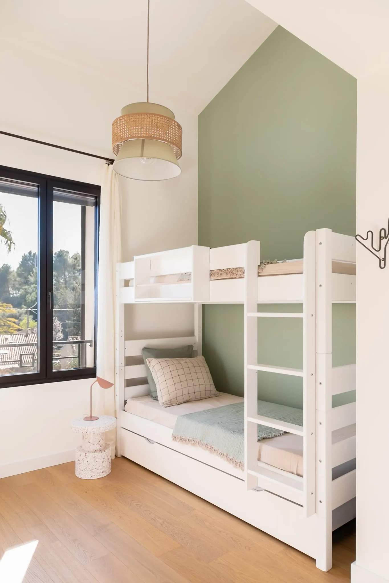 chambre enfant avec lit superposé peinture murale verte et suspension lumineuse en rotin rideaux en lin fenêtre avec garde-corps sur mesure