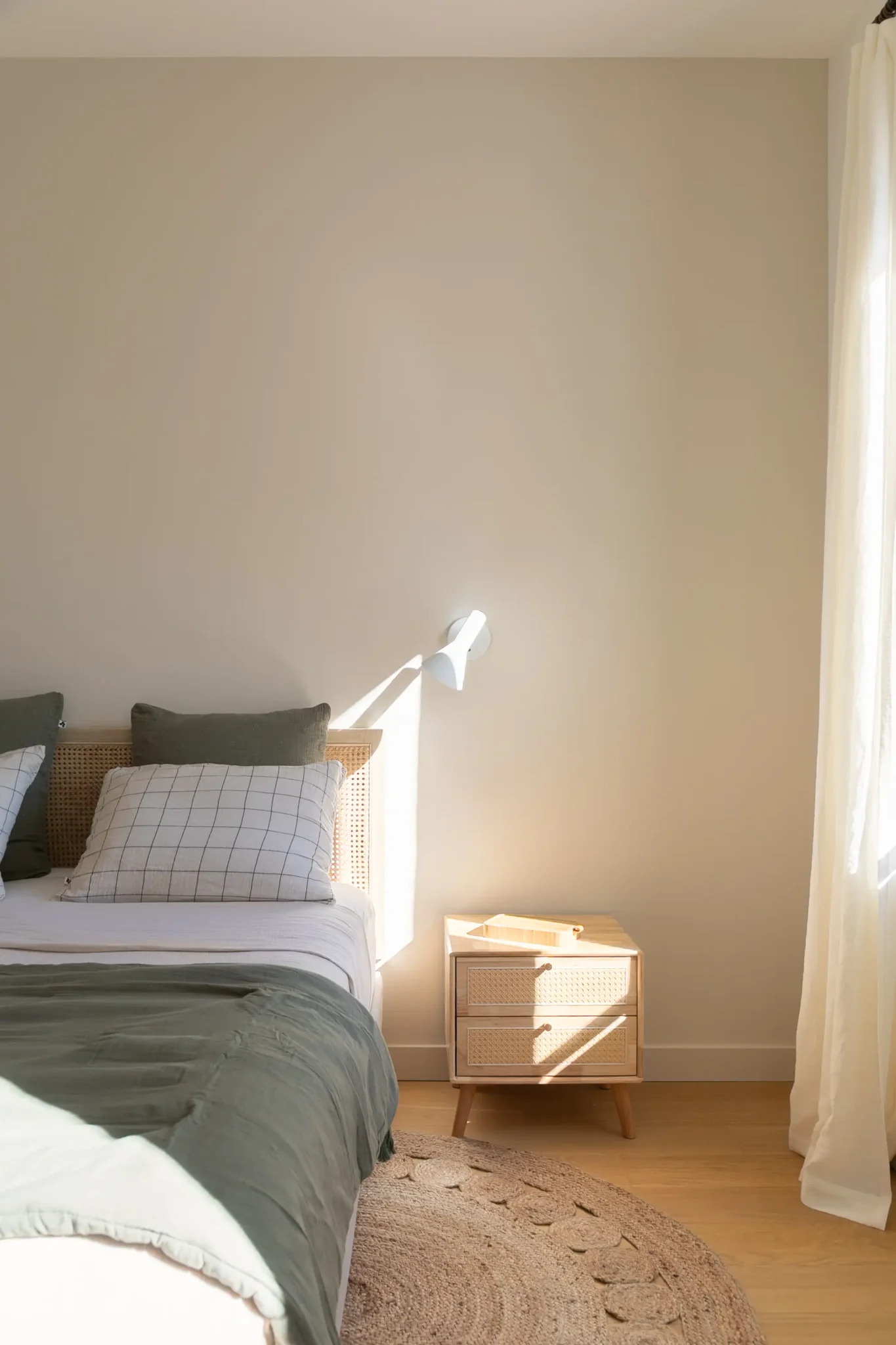 chambre avec sol en parquet rideaux en lin tête de lit en rotin et tapis rond décoration chambre draps de lit vert en lin