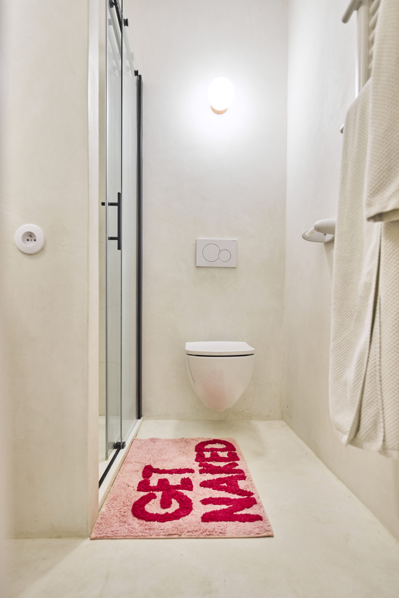 salle e bains avec douche sol et mur en béton ciré wc suspendu applique murale la quincaillerie moderne verre mat porte de douche noir prise ronde travaux rénovation maison Aix en Provence