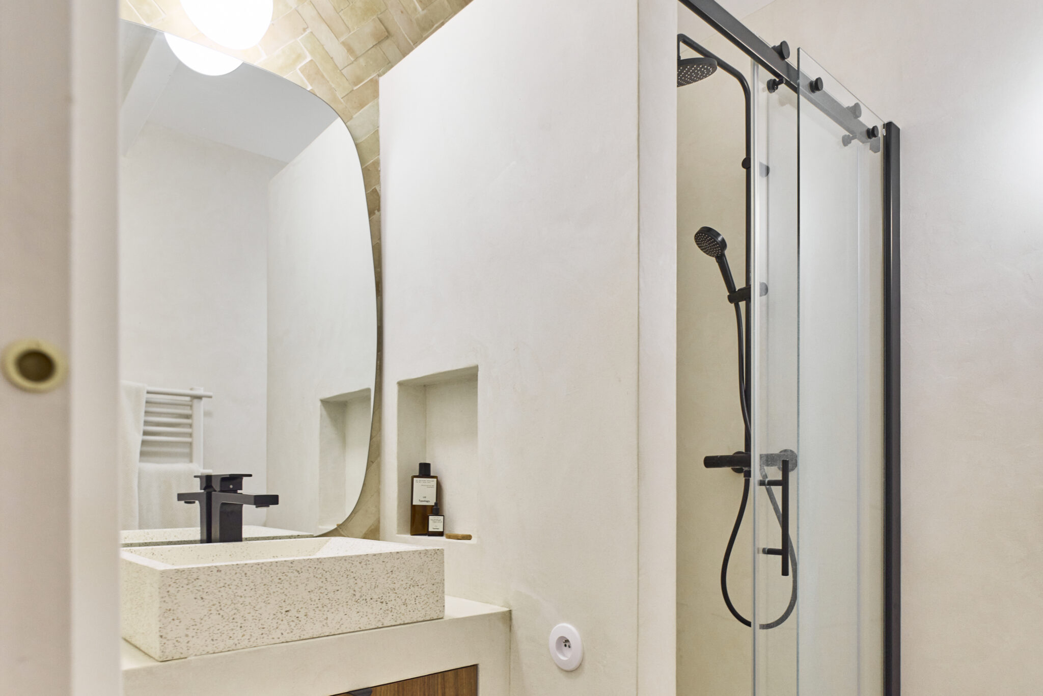 une salle de bains avec béton ciré mural et bejmats pose chevron et meuble vasque maçonné enduit béton ciré rénovation maison provençale à Aix en Provence